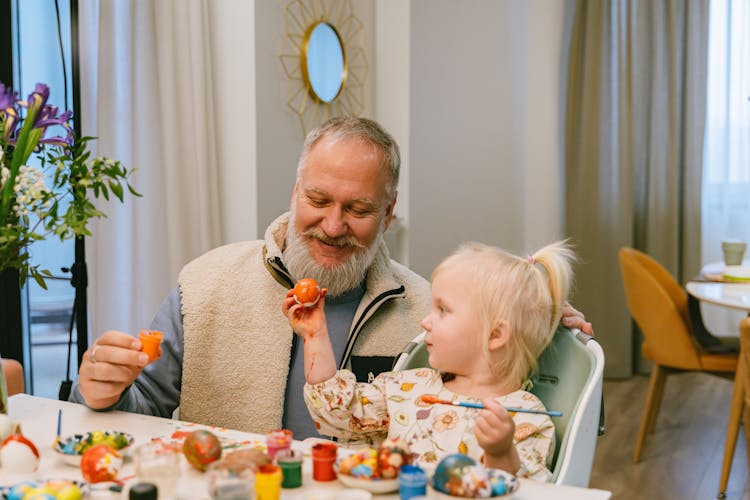 A Grandfather And A Child Painting Eggs