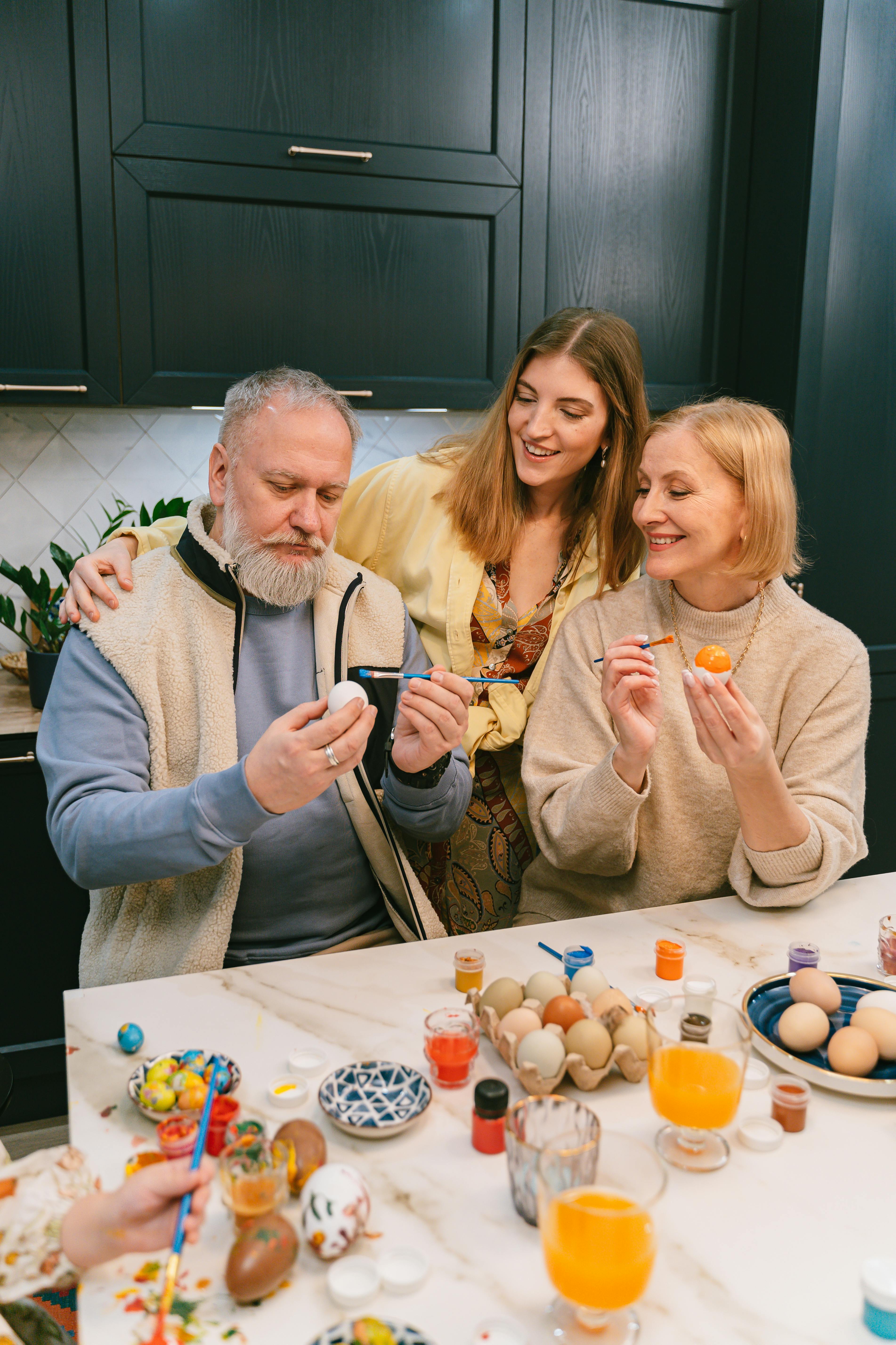 A family enjoying Easter egg painting together in a cozy kitchen setting.