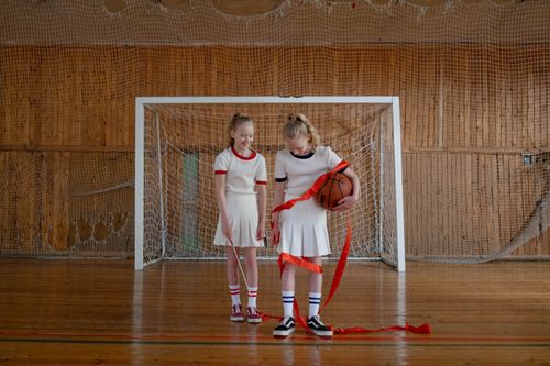 Free Two young girls standing in a gym celebrating with a basketball and ribbon. Stock Photo