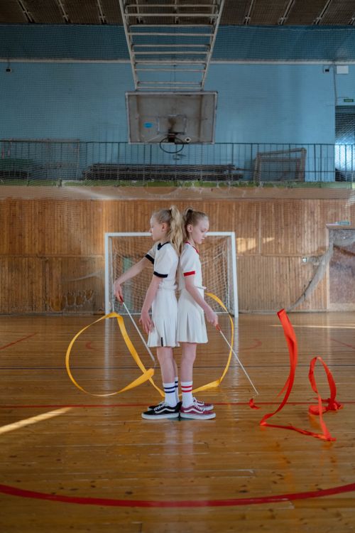 Free Two young gymnasts performing synchronized ribbon routines indoors on a sports court. Stock Photo