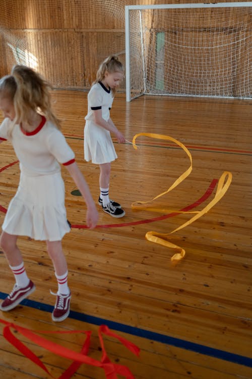Free Two girls practicing rhythmic gymnastics with ribbons on an indoor court. Stock Photo