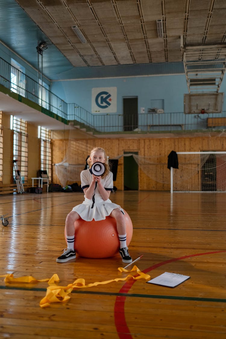 Girl Sitting On A Gym Ball While Using A Loudspeaker