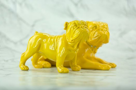 Close-up of yellow bulldog ornaments on a marble-like surface, showcasing glossy ceramic details.
