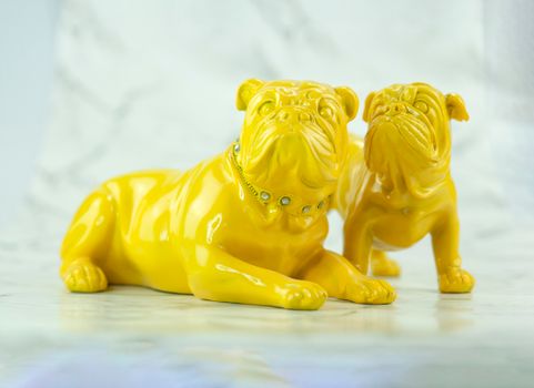 Vibrant yellow bulldog figurines placed on a marble background, evoking a modern still life feel.