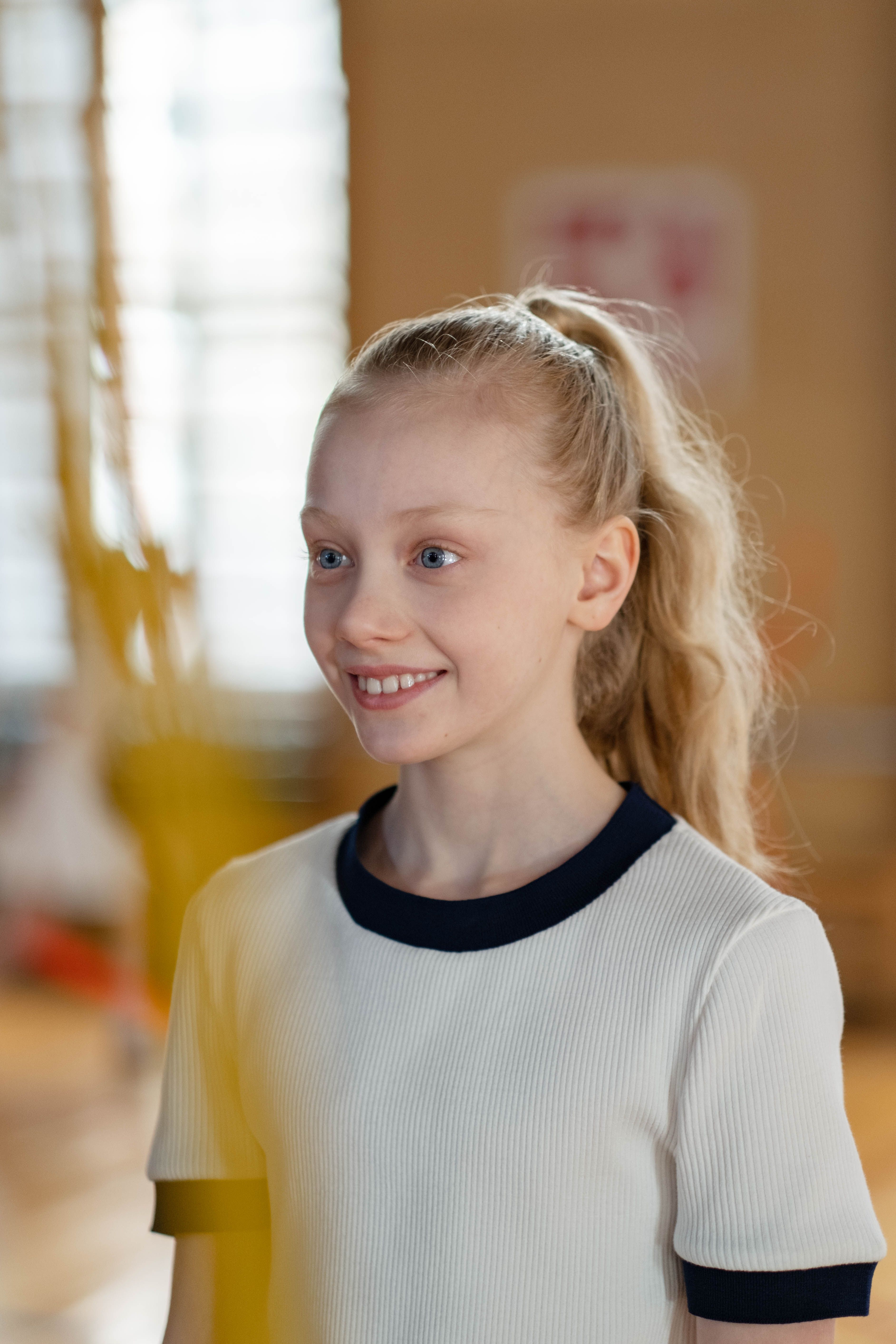 Cheerful young girl smiling indoors in a casual setting.