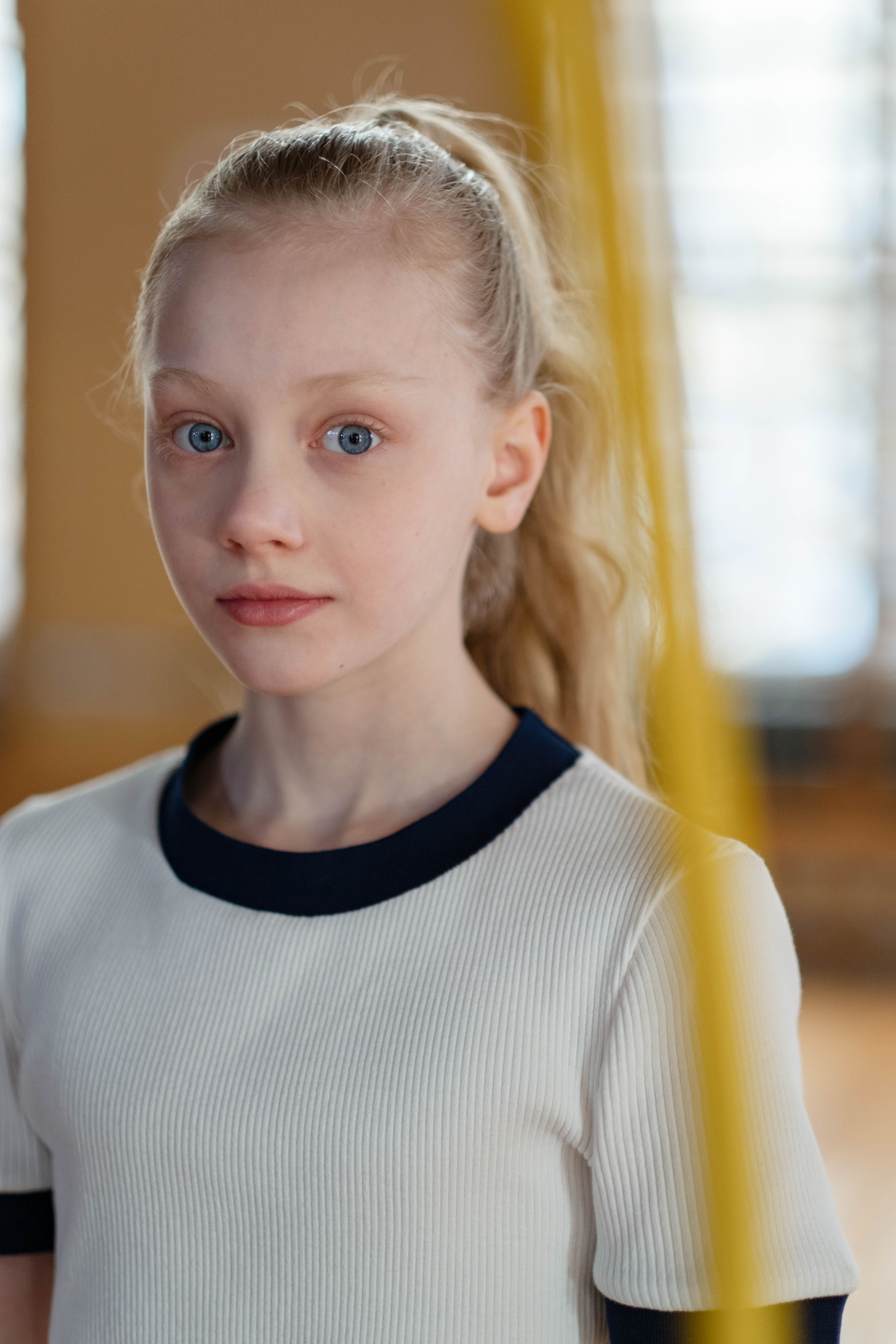 Close-up portrait of a young blonde girl with a neutral expression.