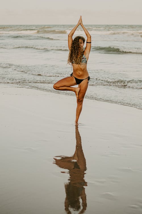 Woman Standing on the Beach Doing Yoga Pose