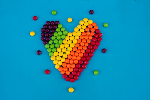 蓝色背景上，一颗由彩色糖果制成的心形图案，象征着爱与欢乐