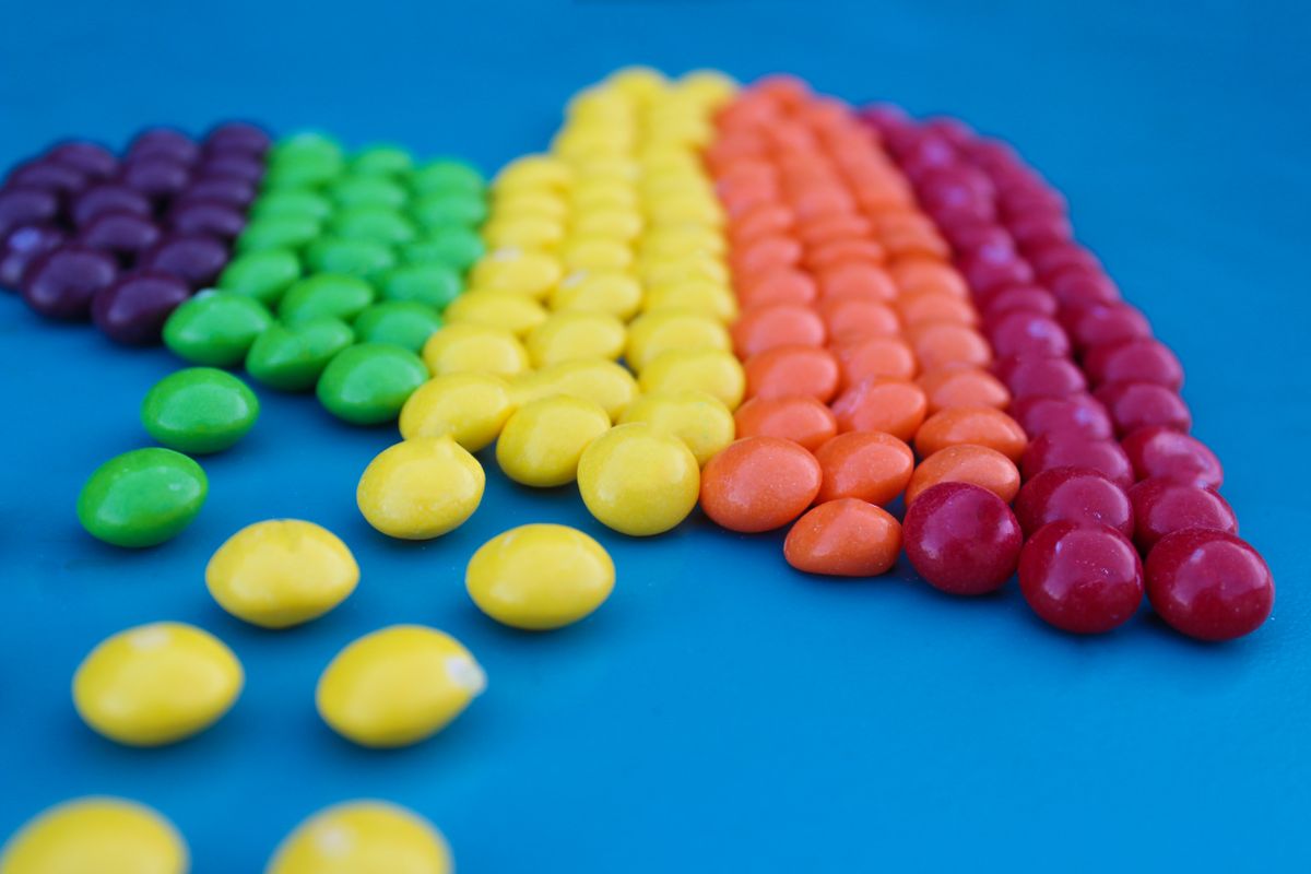 Close-up of colorful candies arranged in rows on a vibrant blue surface.