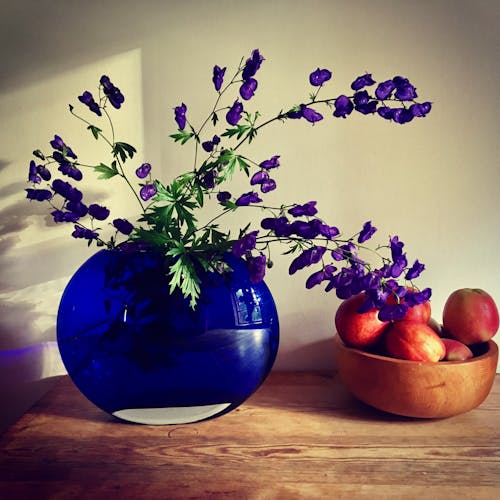 Arreglo Floral De Pétalos De Color Púrpura Cerca De La Fruta De Manzana En La Mesa