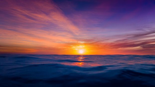 Dramatic sunset over the ocean with vivid colors reflecting on calm water.