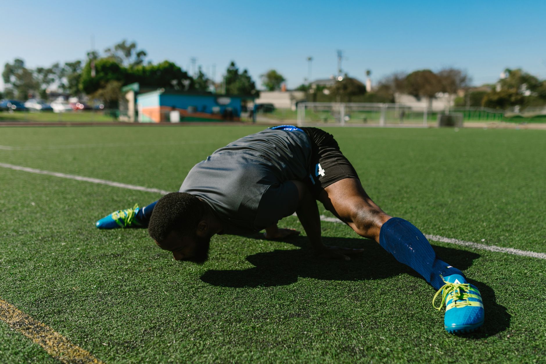 footballer performing dynamic warm-up drills on a wet training pitch at sunrise