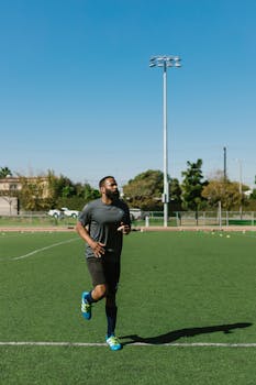 A Black male athlete jogging on a green field, showcasing outdoor fitness and athletic training.