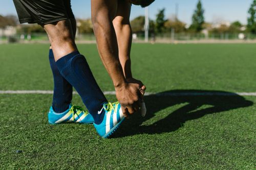 Free Athlete preparing with stretches on a green soccer field during a sunny day. Stock Photo