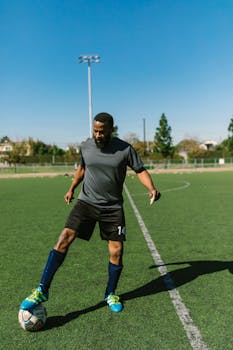 Adult male soccer player practicing on a sunny day at an outdoor field, showcasing athletic skills.