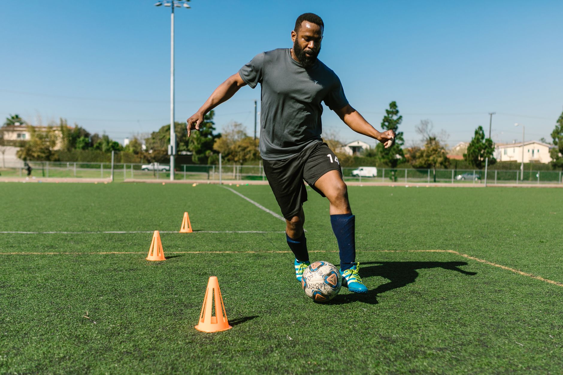 Football cones arranged in a narrow zigzag while a midfielder uses alternating foot touches