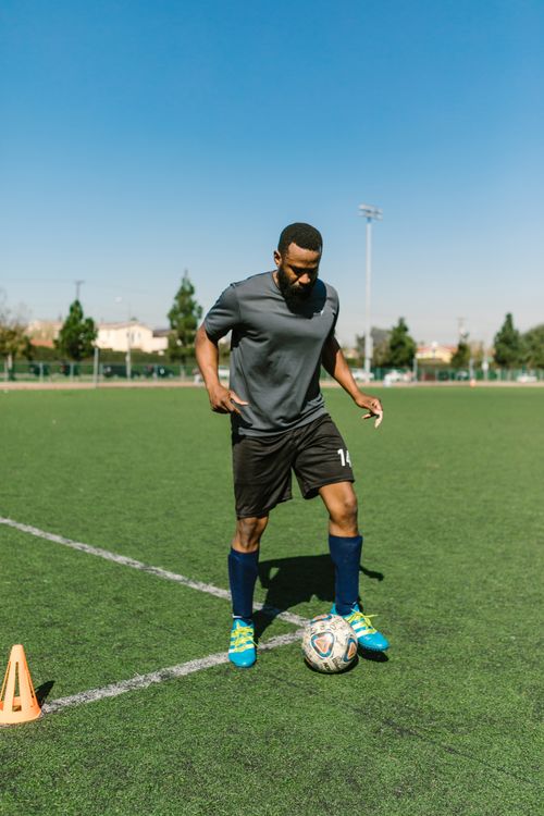 Free Athletic man practicing soccer skills on a sunny day outdoors on a green sports field. Stock Photo