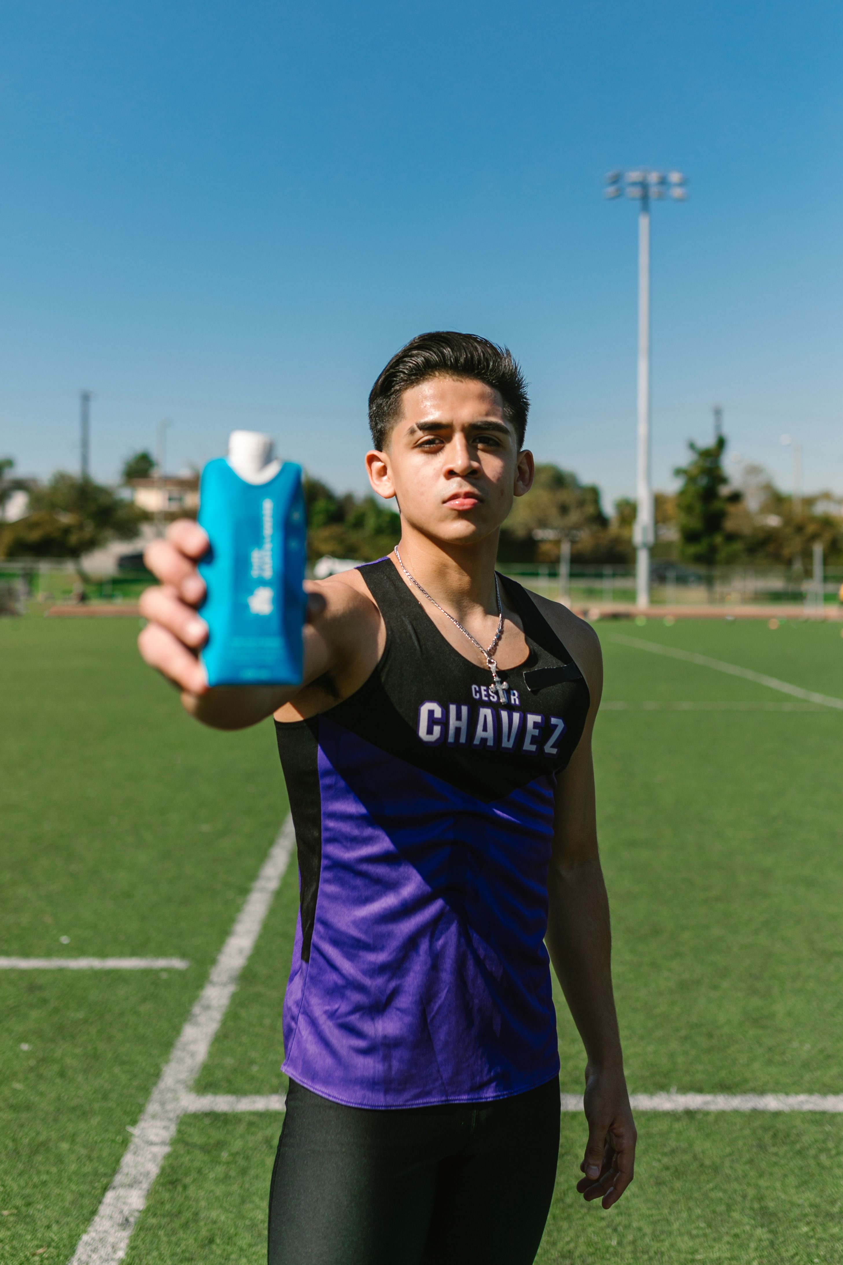 Athlete showing a hydration pouch on a sunny day in the park.