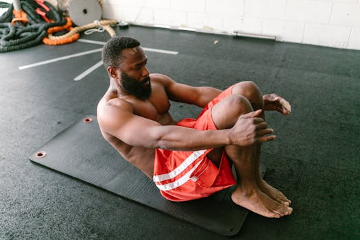 A physically fit man doing sit-ups on a mat indoors, focusing on core strength.