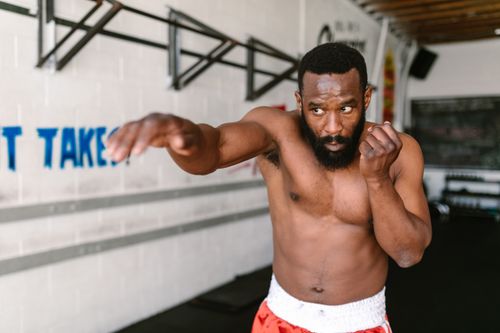 Free Focused African American man practicing shadow boxing in a well-lit gym interior. Stock Photo