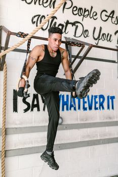 A focused athlete showcases strength and agility with a ring workout in the gym.