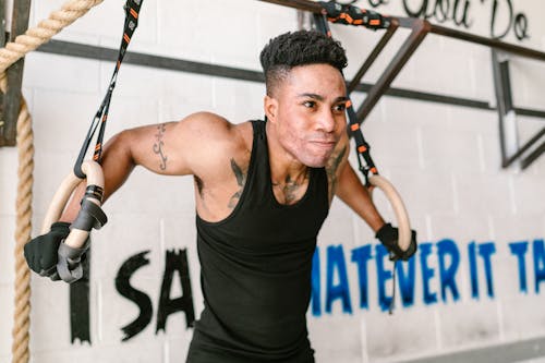 Man in Black Shirt Hanging on Gymnastic Rings