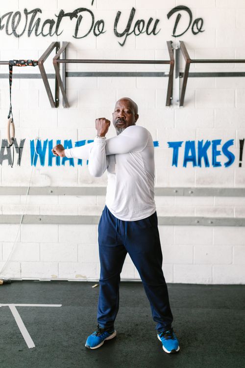 Free Senior man stretching arms in gym setting, promoting active lifestyle and fitness. Stock Photo