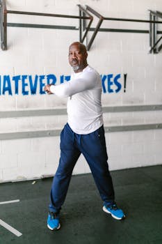 Senior man in gym doing a warm-up stretch indoors for a workout.