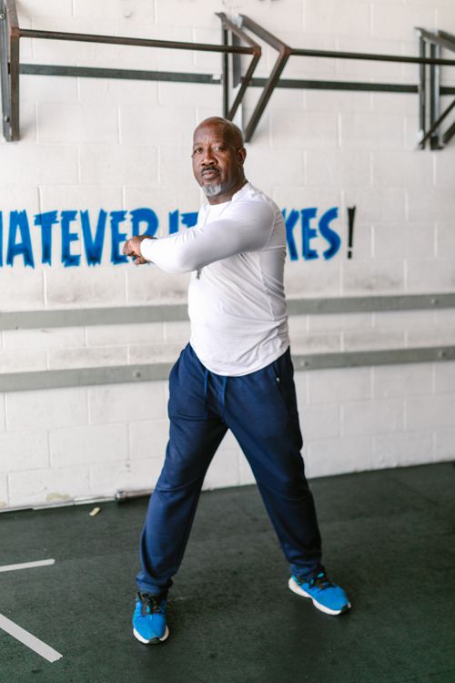 Free Senior man in gym doing a warm-up stretch indoors for a workout. Stock Photo