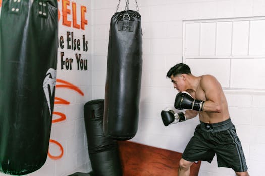 A young boxer practicing with a punching bag inside a gym, focusing on fitness and training skills.