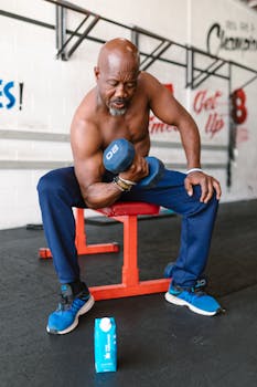 Fit senior man lifting dumbbells indoors, showcasing strength and fitness.