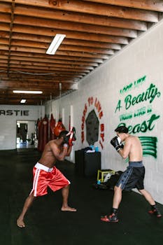 Two men engaged in a focused boxing training session indoors, showcasing skill and strength.