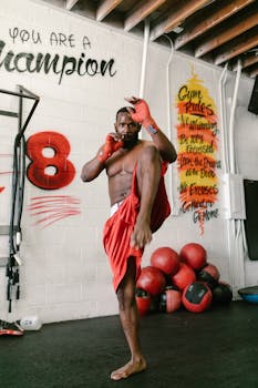 Strong athlete practicing kickboxing in a gym with motivational quotes.