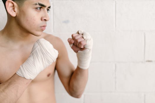 Focused young male boxer with hand wraps in fighting stance, ready for training.