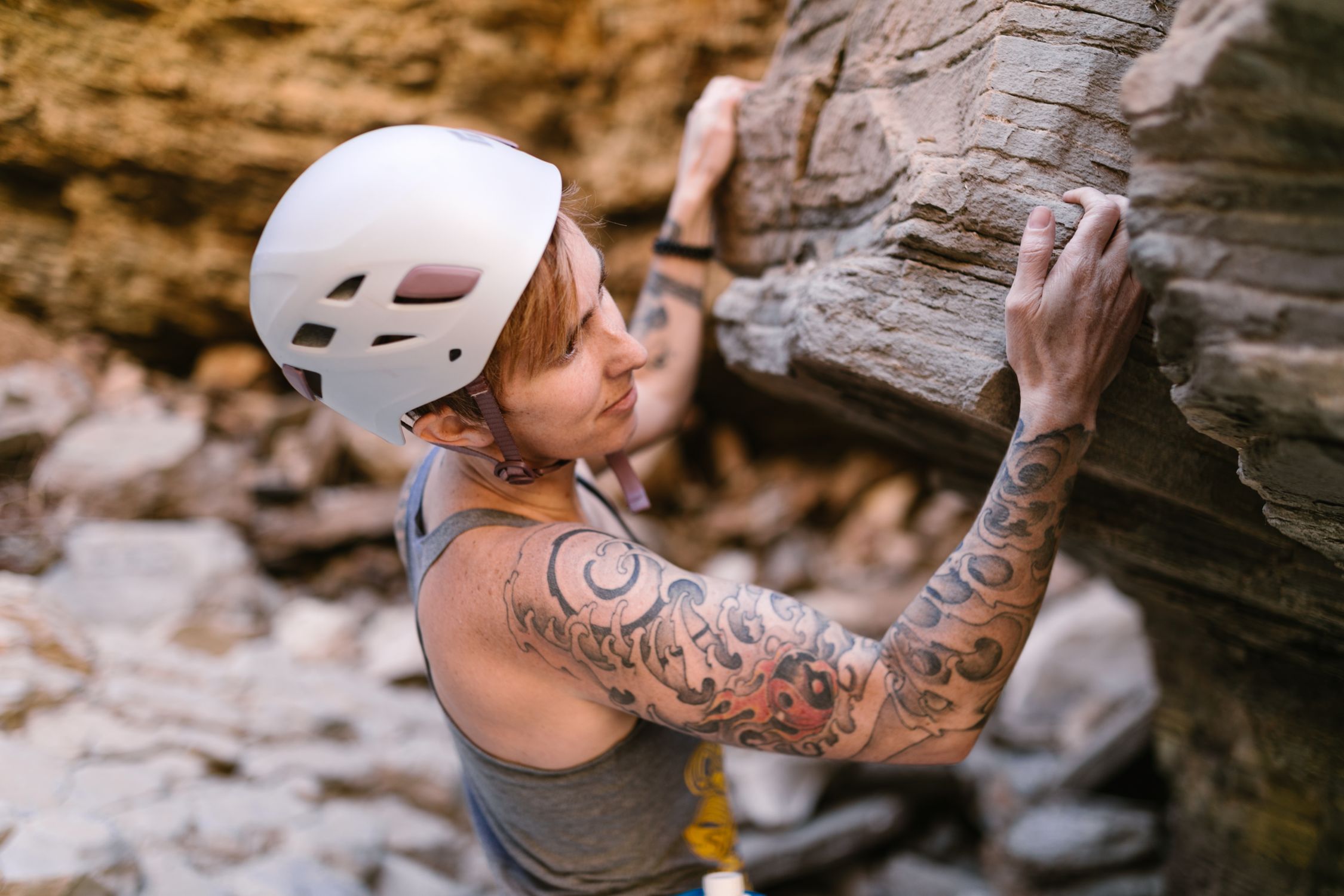 Focused woman climbing an outdoor rock formation with safety helmet