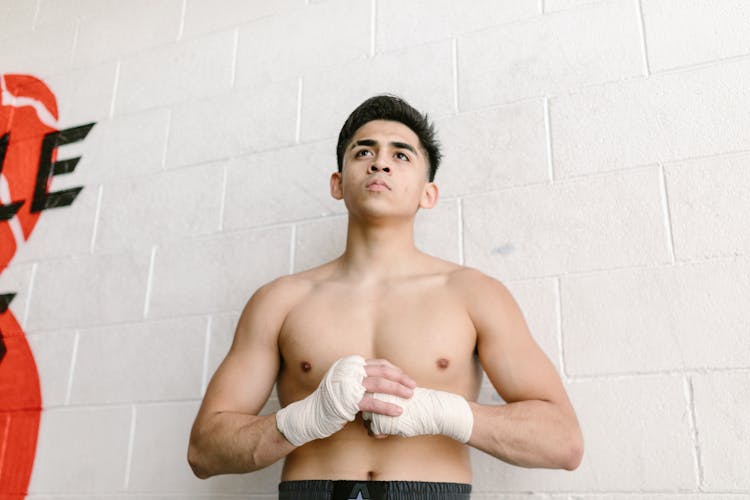 A Portrait Of A Shirtless Man In Hand Wraps