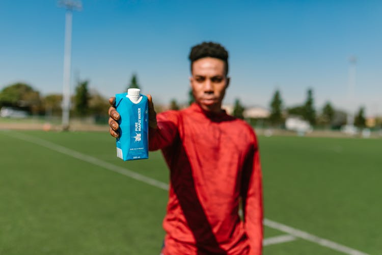 Shallow Focus Photo Of A Man Showing A Product Of Pure Maple Water