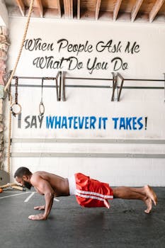 Athlete exercising indoors in gym with motivational wall text.