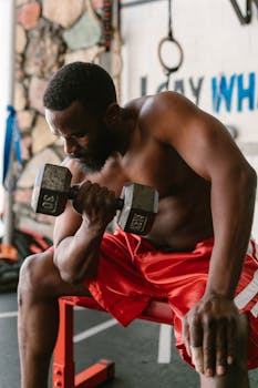 Muscular man working out with dumbbell, showcasing strength and focus.