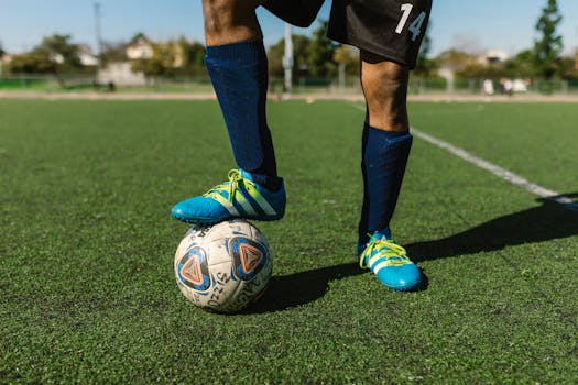 Close-up of a soccer player with a ball on a green field, showcasing athletic footwear and sporting activity.