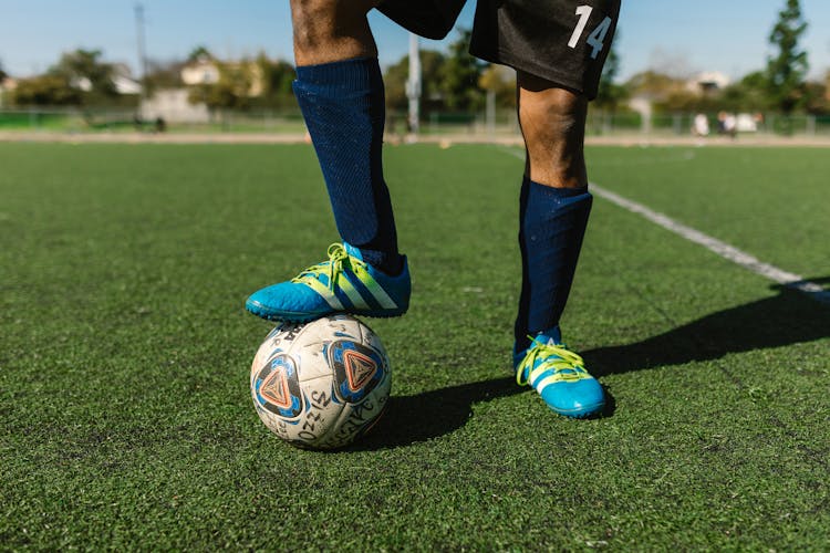 Man In Blue Sneakers Standing With Foot On Soccer Ball 