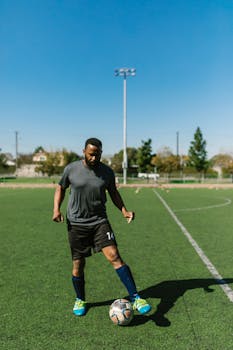 An African American man trains on a sunny day at an outdoor soccer field.