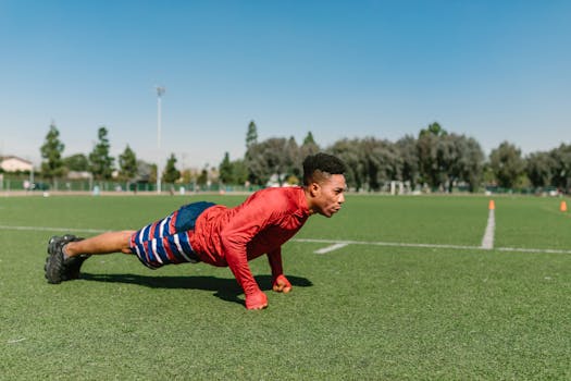 African American man performs push-ups on a sunny soccer field during a workout session.
