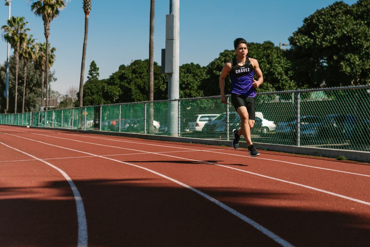 A solo runner on a red track training with knee support in mind