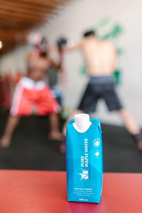 Free A maple water drink with boxers training in the blurred background, emphasizing hydration. Stock Photo