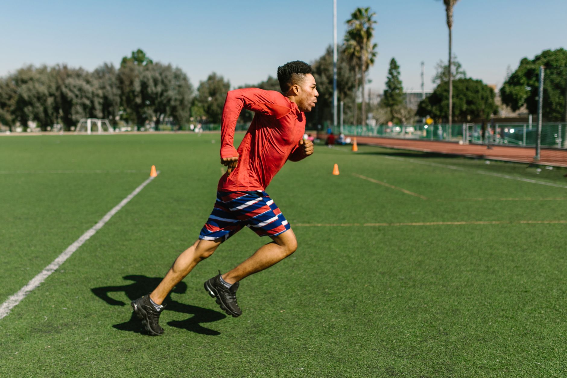 winger sprinting through agility cones on a wet football pitch, intense competitive atmosphere