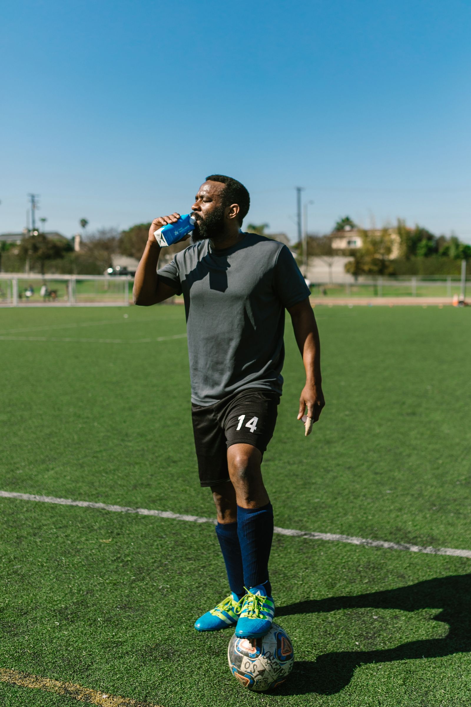 An athlete drinking water on a sports field during a break