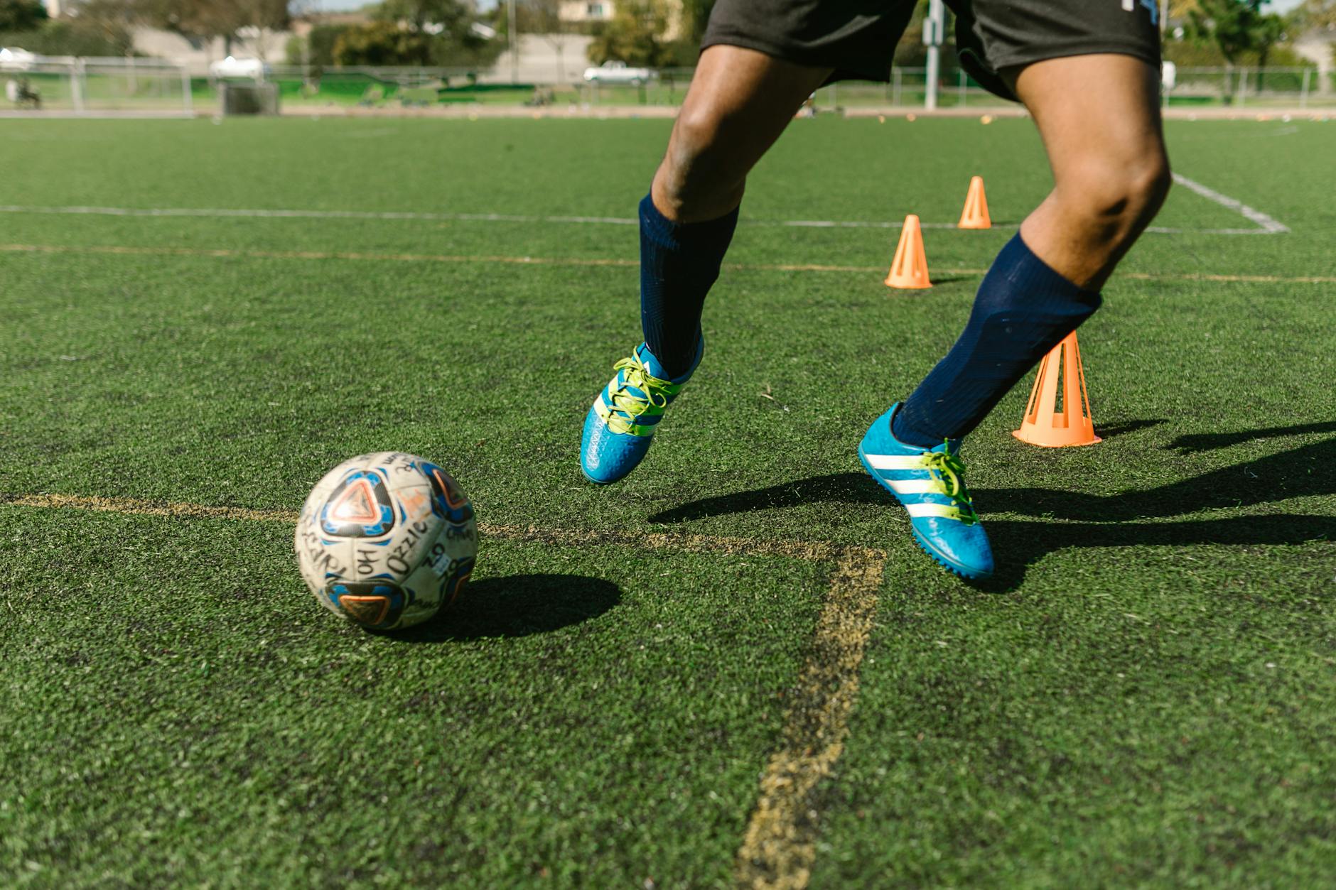 How to Get the Best Deals at Dick’s Sporting Goods: Tips and Tricks Dynamic image of a soccer player practicing drills on a grass field with vibrant shoes and cones.