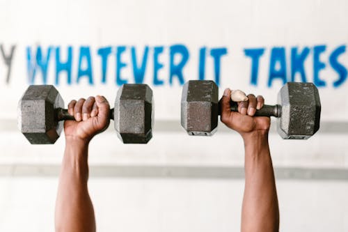 Shallow Focus Photo of Person Lifting Two Heavy Dumbbells
