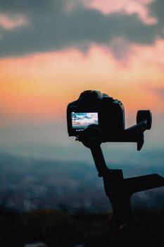 Silhouette of a DSLR camera capturing a stunning sunset view with vibrant sky colors.